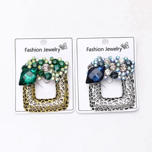 Detail of vintage square crystal brooches in gold emerald and silver sapphire styles