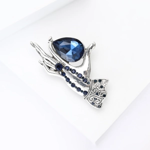 Macro view of vintage silver hand brooch holding a large teardrop blue crystal gem