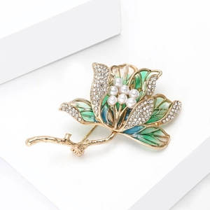 Dettaglio della spilla a fiore in smalto con strass e perle su base geometrica bianca