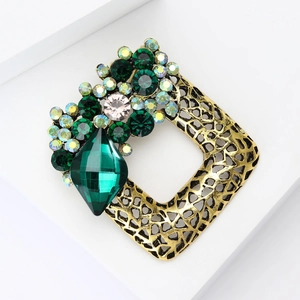Macro detail of luxury vintage square brooch with green crystals and gold filigree base