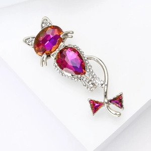 Close-up of glass cat brooch with pink gradient crystal and silver bow detail