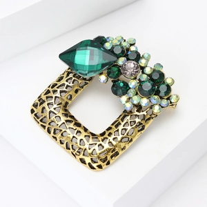 Detail view of a vintage gold square brooch featuring green crystals and sparkling rhinestones