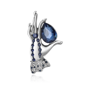 Elegant silver hand-shaped brooch holding a large pear-cut blue crystal gemstone
