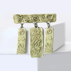 Vintage totem broche met vogelgravure in retro gouden afwerking op wit voetstuk