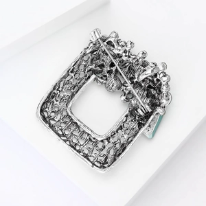 Macro view of vintage silver hollow brooch with safety pin clasp and blue detail