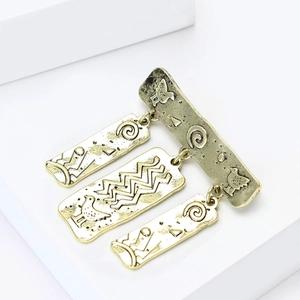 Detail van vintage gouden totem hangers met tribale vogels in reliëf en geometrische patronen