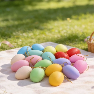 Set mit 20 bunten Osterdekoreiern mit goldenen Aufhängeschnüren auf natürlichem Grasgrund