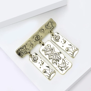Macro-opname van de vintage gouden broche met drie hangers met gegraveerde patronen