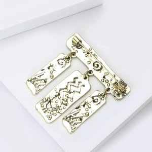 Detail van vintage gouden totem broche met drie rechthoekige hangende hangers erop