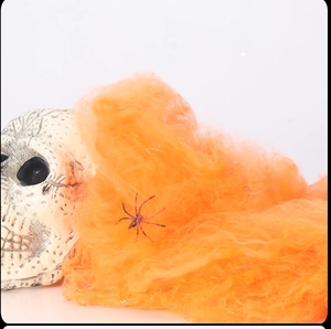 Detail van rekbaar oranje spinnenweb met een zwarte spin op een decoratieve schedel