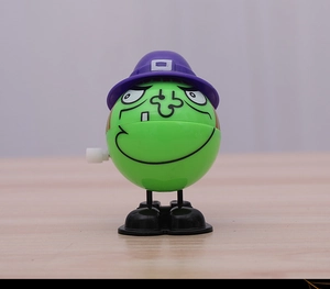 Detail of green monster wind-up toy with purple top hat and mechanical side knob