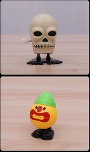 Macro view of wind-up clockwork skeleton and clown head jumping toys for kids
