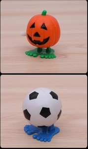 Detail view of wind-up toys showing orange pumpkin and soccer ball with walking feet