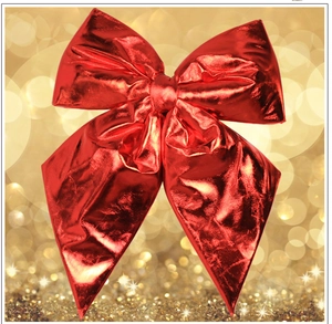 Close-up of a metallic red decorative Christmas bow with a glossy finish and bokeh background