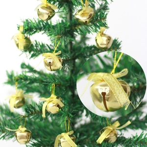 Detail of a gold Christmas bell with a golden bow hanging on a green tree branch