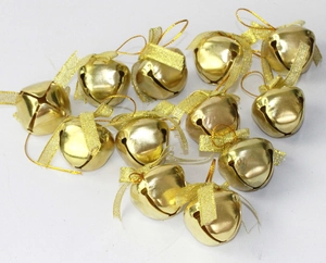Flat lay of golden Christmas jingle bells with shimmering bows and hanging loops on white