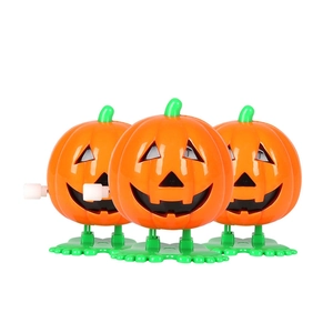 Three orange wind-up Halloween pumpkin toys with green legs on a white background