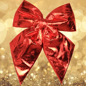 Large festive red metallic bow decoration with sparkling gold bokeh background