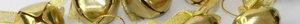 Close-up of golden metal Christmas bells with silk ribbons for festive tree decoration