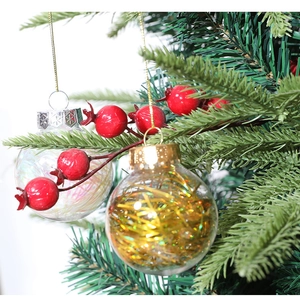 Detail of transparent PET Christmas balls with laser wire and red berries on a pine tree