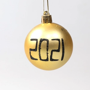Golden Christmas ball ornament with black 2021 glitter lettering on white background