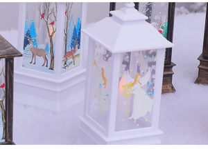 Macro detail of Christmas lanterns with reindeer and angel patterns on snowy background