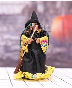 Detail of Halloween witch doll decoration with black robe, yellow stars and a mini broom