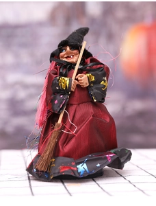 Detail of Halloween witch doll in red satin robe with golden bat patterns and broom