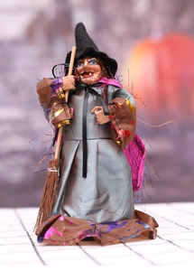 Detail of Halloween witch doll with grey silk robe, pointed hat and small broomstick