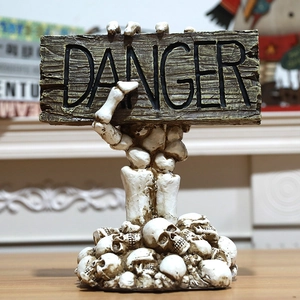 Detailed resin Halloween skeleton hand holding a vintage Danger sign on a skull base