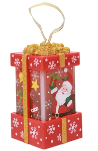 Detailed view of a red Christmas gift box ornament with gold glitter ribbon and snowflake patterns
