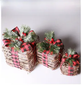 Close-up of three lighted rattan Christmas gift boxes with berries and plaid bows