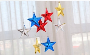 Close-up of shiny gold, silver, red, and blue hanging star ornaments for festive decoration