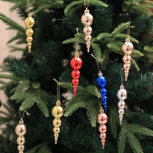 Colorful electroplated icicle ornaments hanging on a green Christmas tree branch
