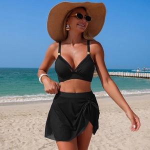 Detail of black two-piece bikini with V-neck halter top and gold hardware on a beach
