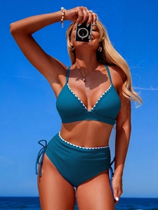 Detail of teal high-waisted bikini set featuring white scalloped trim and side drawstrings