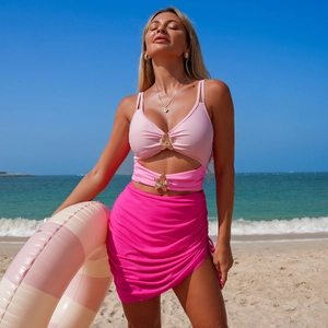 Detail of pink swimwear featuring floral gold buckles on a sunny tropical beach
