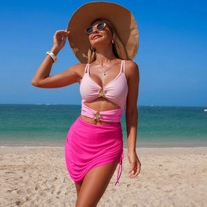 Detail of pink bikini top with gold flower buckles and drawstring swim skirt on beach