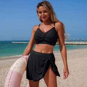 Close-up of black bikini top with front knot and metallic ring on beach background