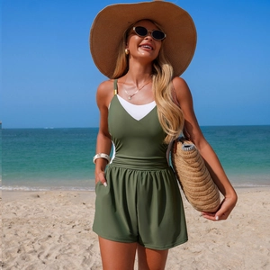 Detail view of olive green one-piece swimwear with white V-neck stitching in beach setting