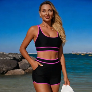 Dettaglio degli shorts bikini neri a vita alta con bordo rosa e pratica tasca laterale