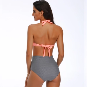 Rear view of coral pink halter bikini top with black and white striped high waisted bottoms