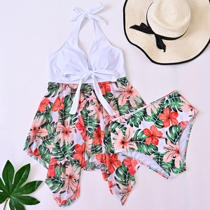 Flat lay of a white halter neck bikini top with tropical floral skirt and matching high waist bottom