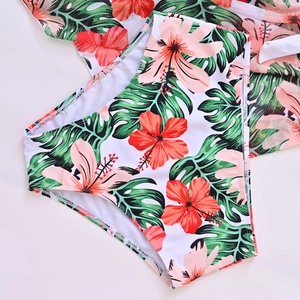 Detail of high-waisted bikini bottoms with vibrant tropical hibiscus and palm leaf print