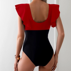 Detail of red and black one-piece swimsuit featuring ruffle shoulders and deep U-back design