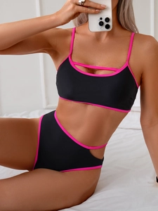 Detail of black bikini with pink piping, featuring waist cut-outs and high-waist fit