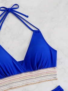 Detail of royal blue halter bikini top featuring colorful wavy embroidered underband trim