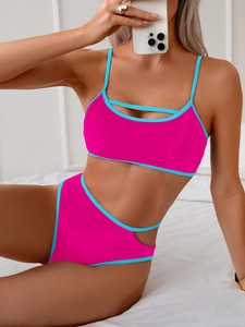 Detail of hot pink bikini with blue trim and cutout details on top and high waist bottom