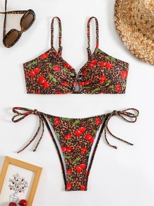 Flat lay of leopard and cherry print bikini set with straw hat and sunglasses