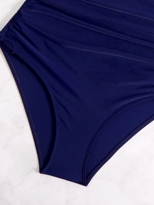 Dettaglio del tessuto arricciato per il controllo della pancia su costume blu scuro